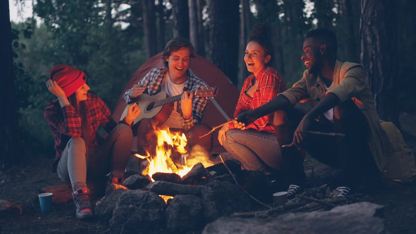 Amigos con guitarra alrededor del fuego